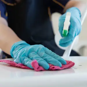 cleaner cleaning a chair with hand protection